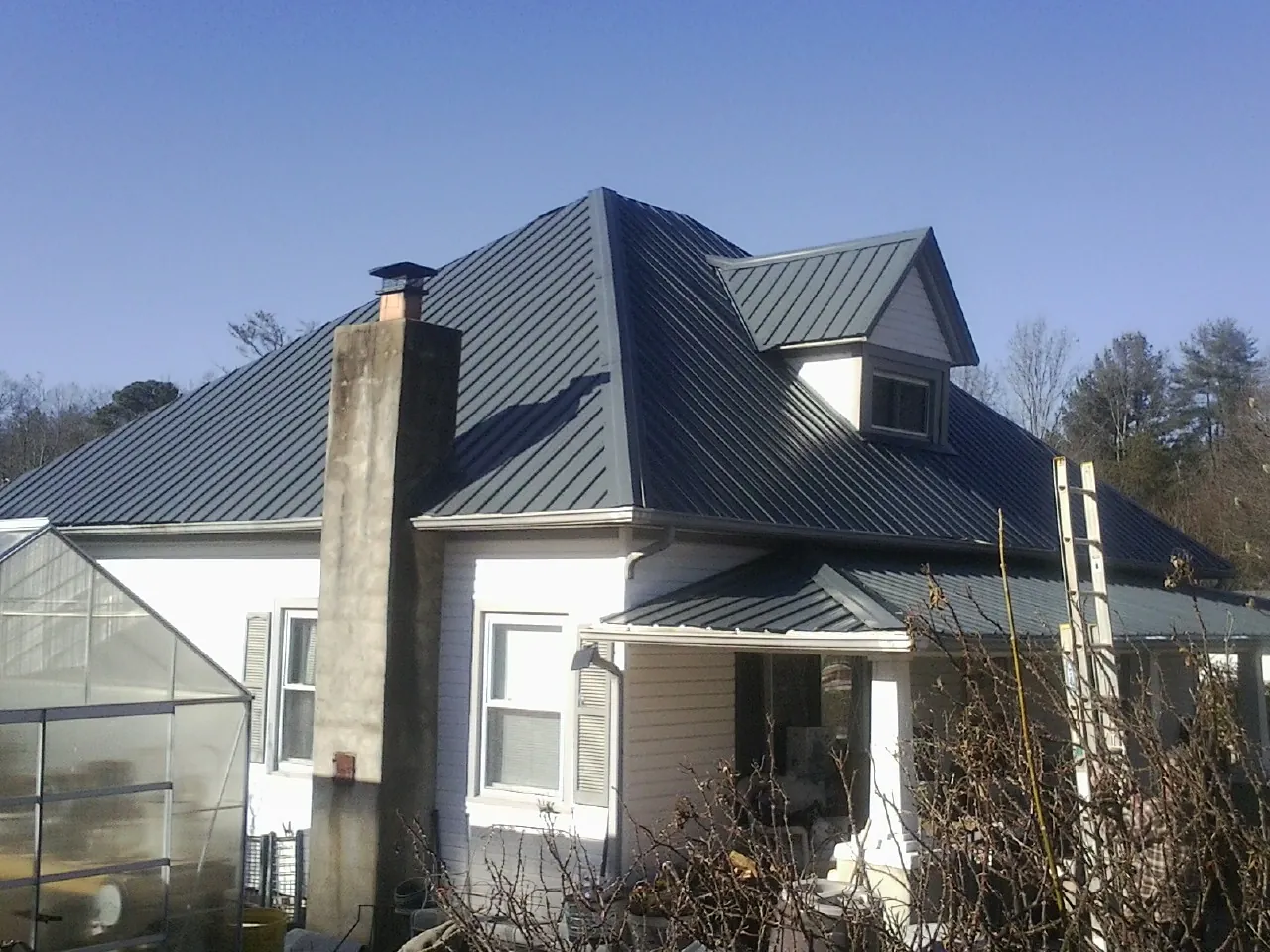 Dark blue standing seam metal roof on a white farmhouse with dormer — Slate & Tile Roof Repair by Roofing Brothers in Ladera Ranch