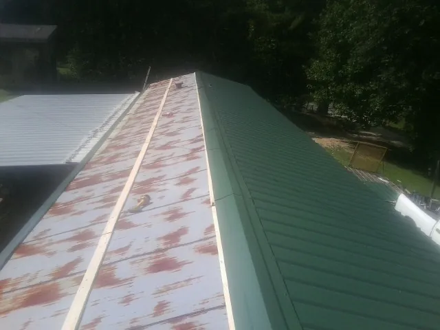 Old rusted panels beside newly installed green metal roofing — Wind Damage Roof Repair by Roofing Brothers in Ladera Ranch