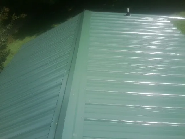 New green metal panels meeting at the ridge of a roof — Flat Roof Repair work by our crew in Ladera Ranch